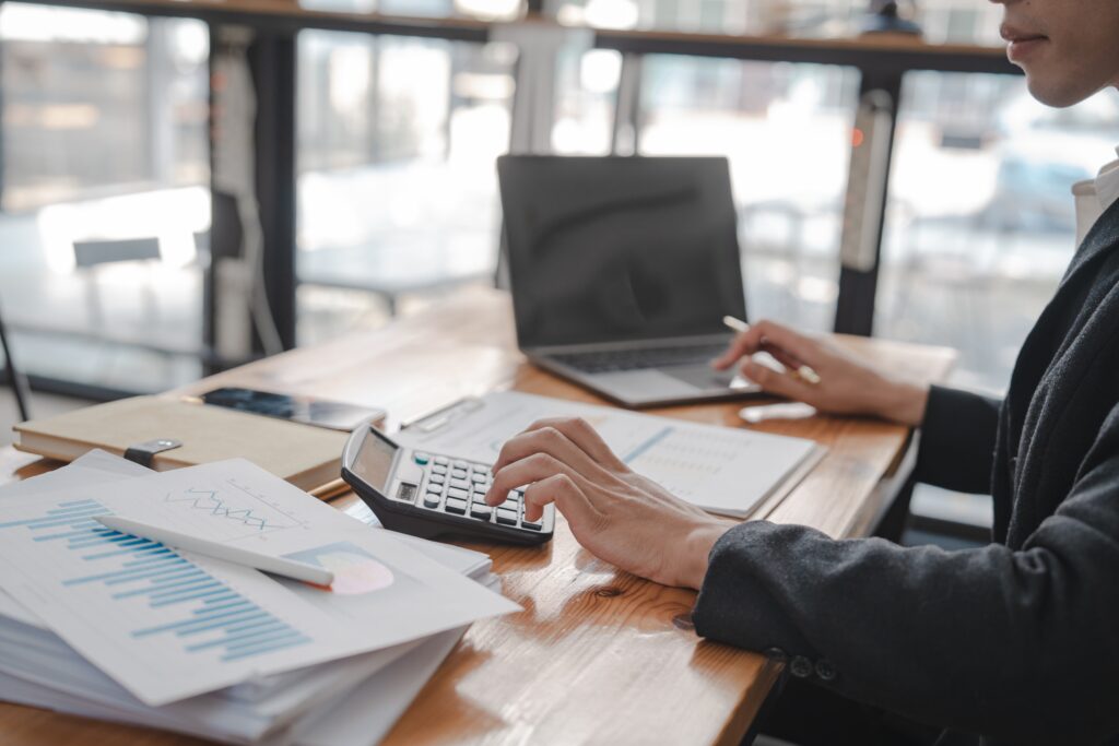 A certified public accountant reviewing documents and typing on a laptop