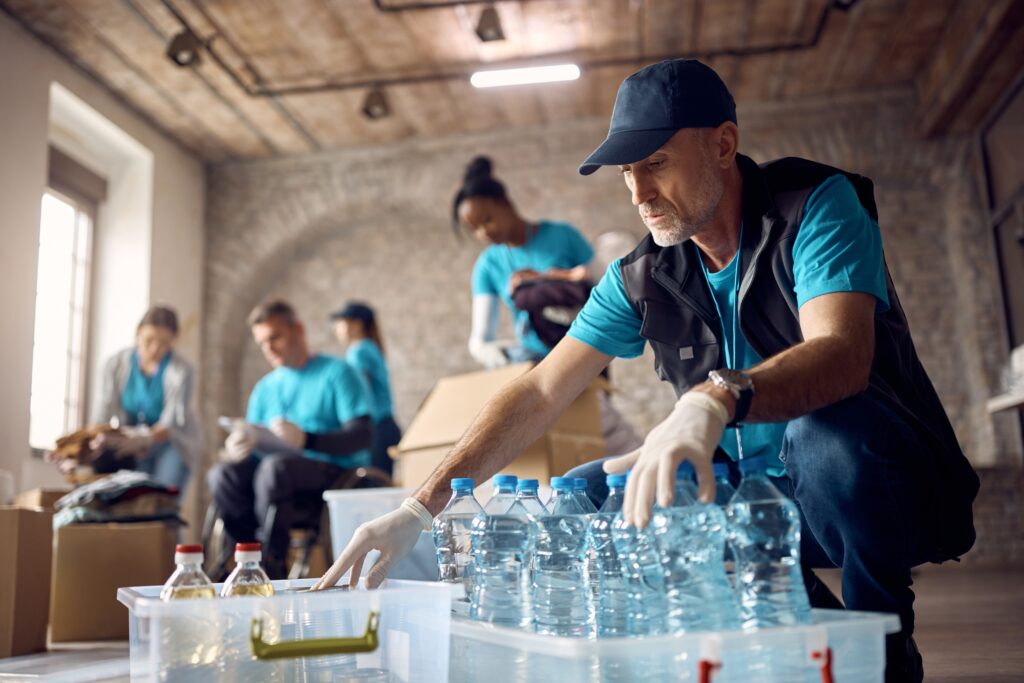 Mature man volunteering and arranging bottles at a community center that undergoes annual nonprofit audits