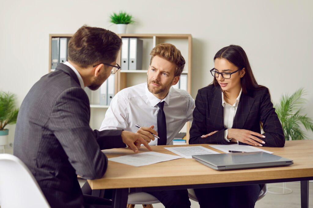 Two men and a woman reviewing franchise fdd disclosure documents together