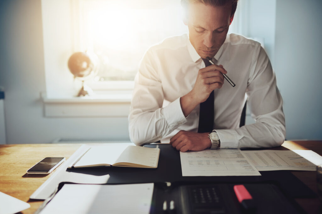 A man highlighting papers in a three ring binder that are for a custody audit