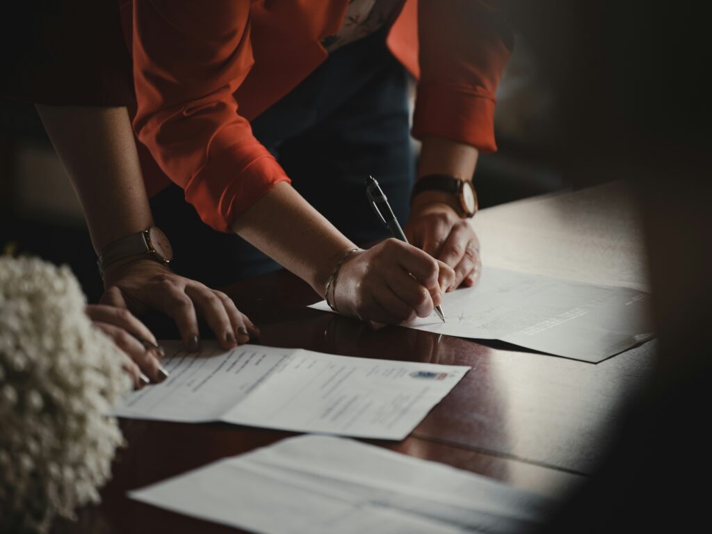 A close up of a woman's hands signing documents for audited financial statements