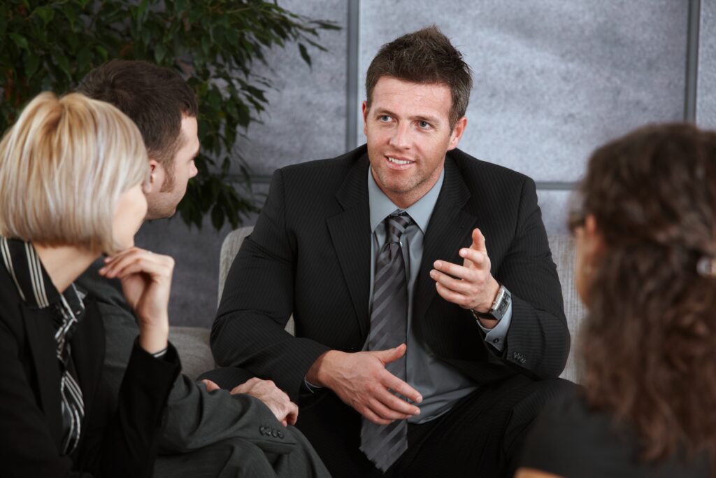 A young business man sitting on a couch explaining what a GAAP audit is to people listening