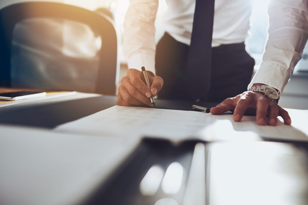 A close up of a businessman signing required financial documents for a statutory audit