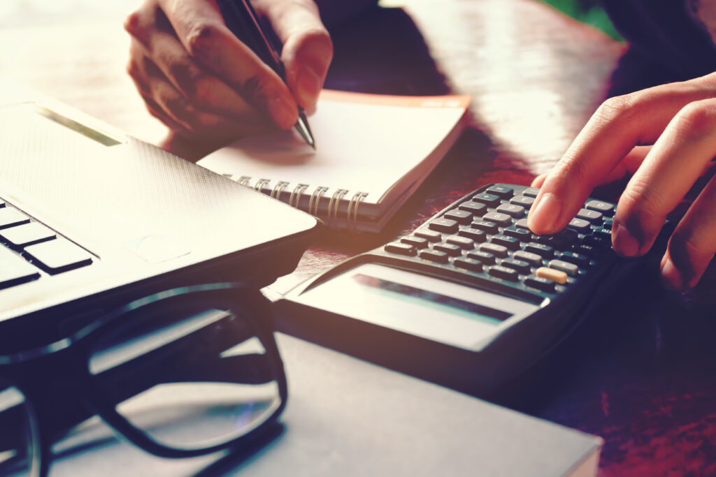 A close up of a woman using a calculator to calculate pricing of services from different 401k audit firms