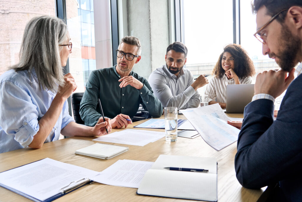 A leadership team at a company discussing how to understand how to meet 401k audit requirements after their recent merger