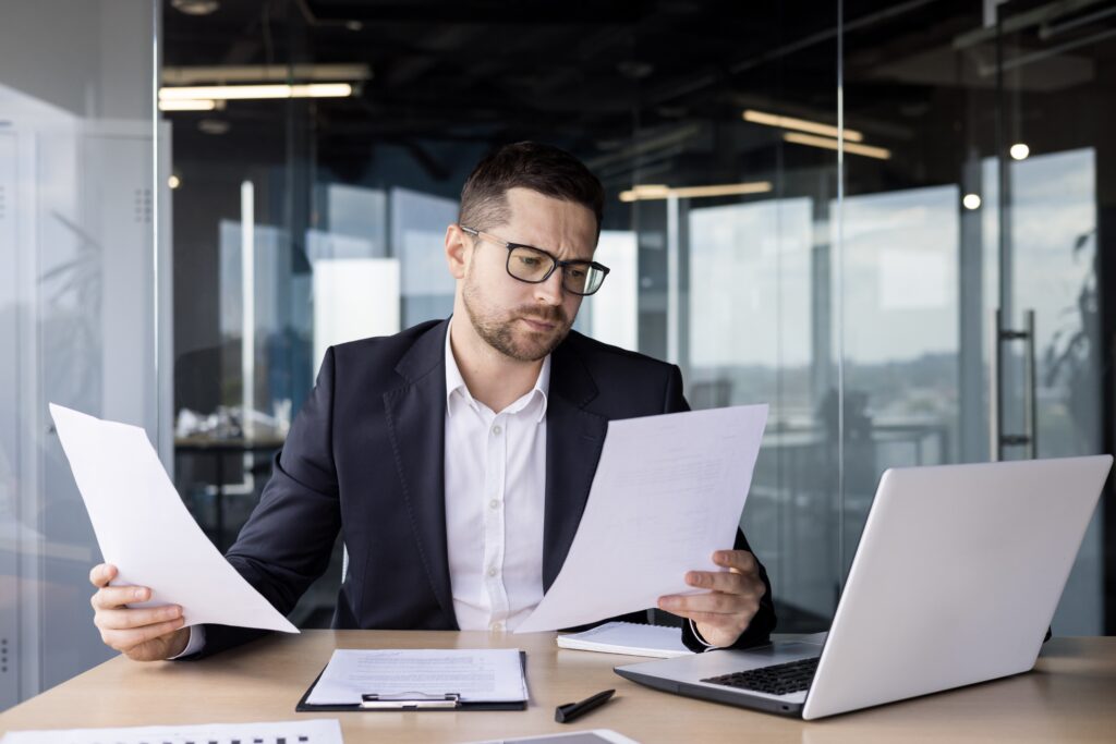 A young business man who is confused while reading financial statements for private audits