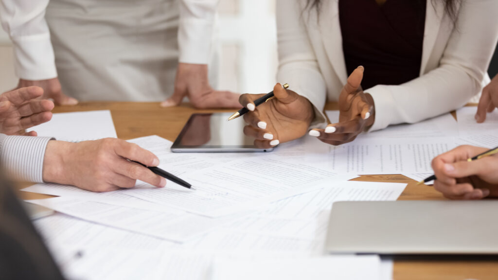 The hands of a team reviewing financial documents that are part of 403b plan audits