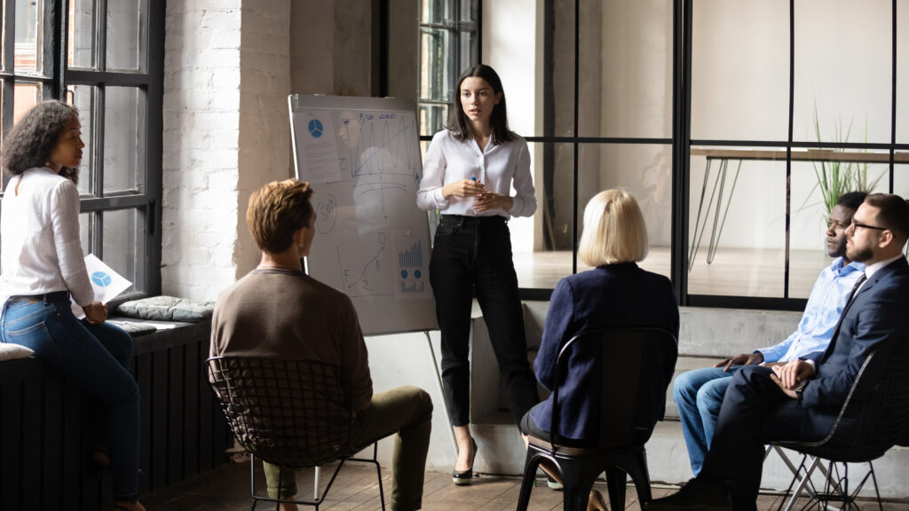 A female investment professional standing in front of a group explaining what a reit is and how to invest in one