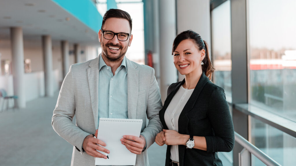 Portrait of audit and assurance professionals smiling at camera while standing in office