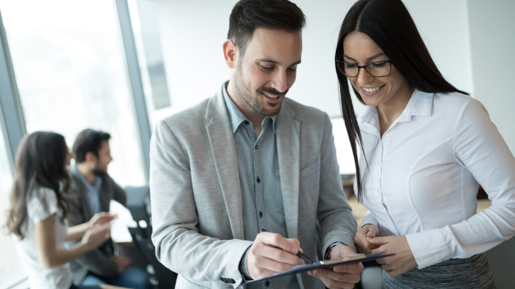 A male audit manager working with female auditor in an office and looking over papers and financial documents