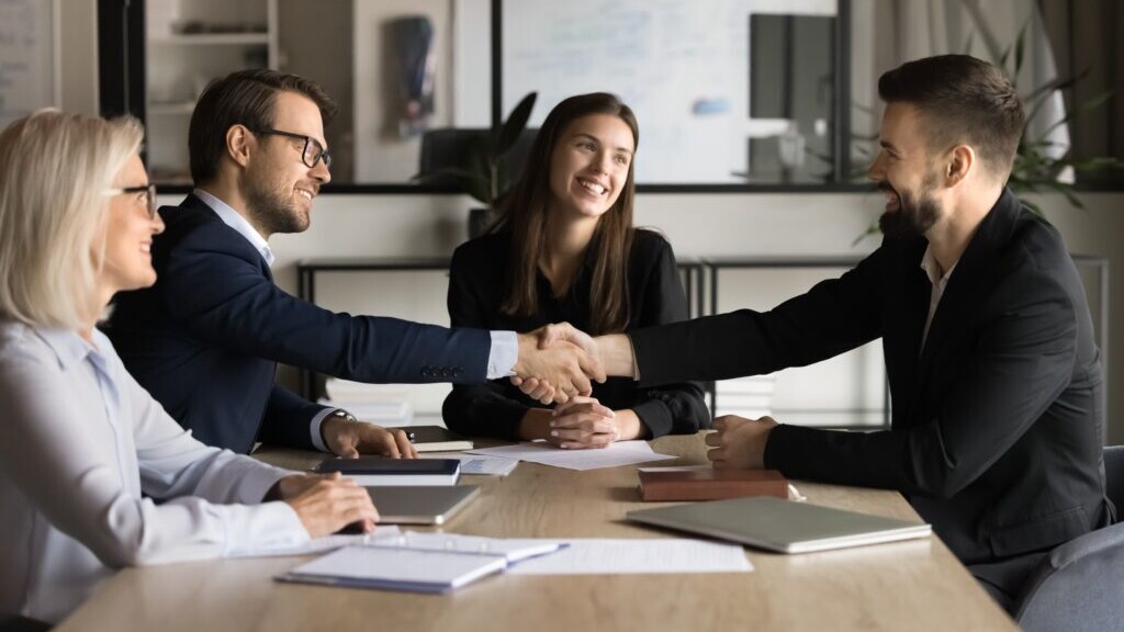 Positive satisfied business colleagues shaking hands with an acccounting firm that will perform audit services