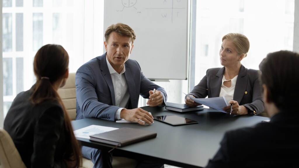 A male senior auditor leading an accounting team meeting on the auditing process for a client