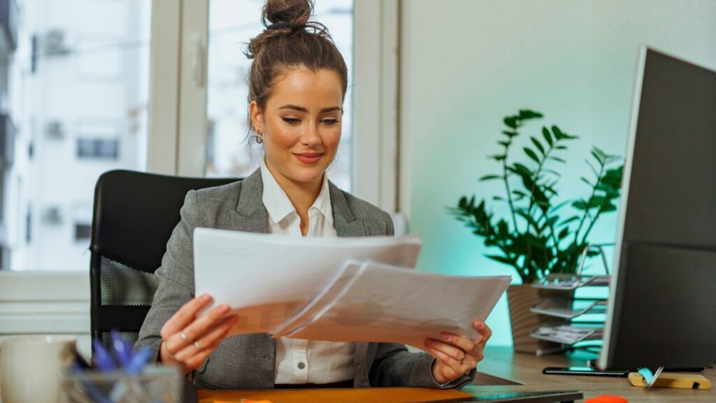 A female staff auditor preparing and adjusting workpapers while sitting at a desk in an office