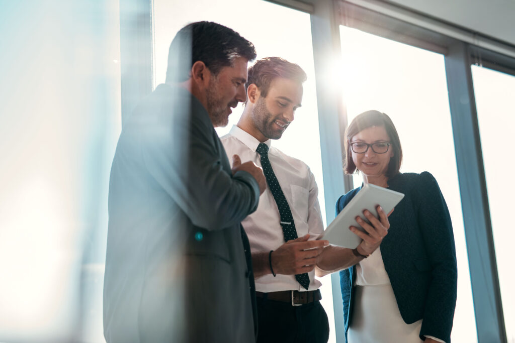 Three professionals reviewing a document on a tablet, discussing a 401k plan audit.