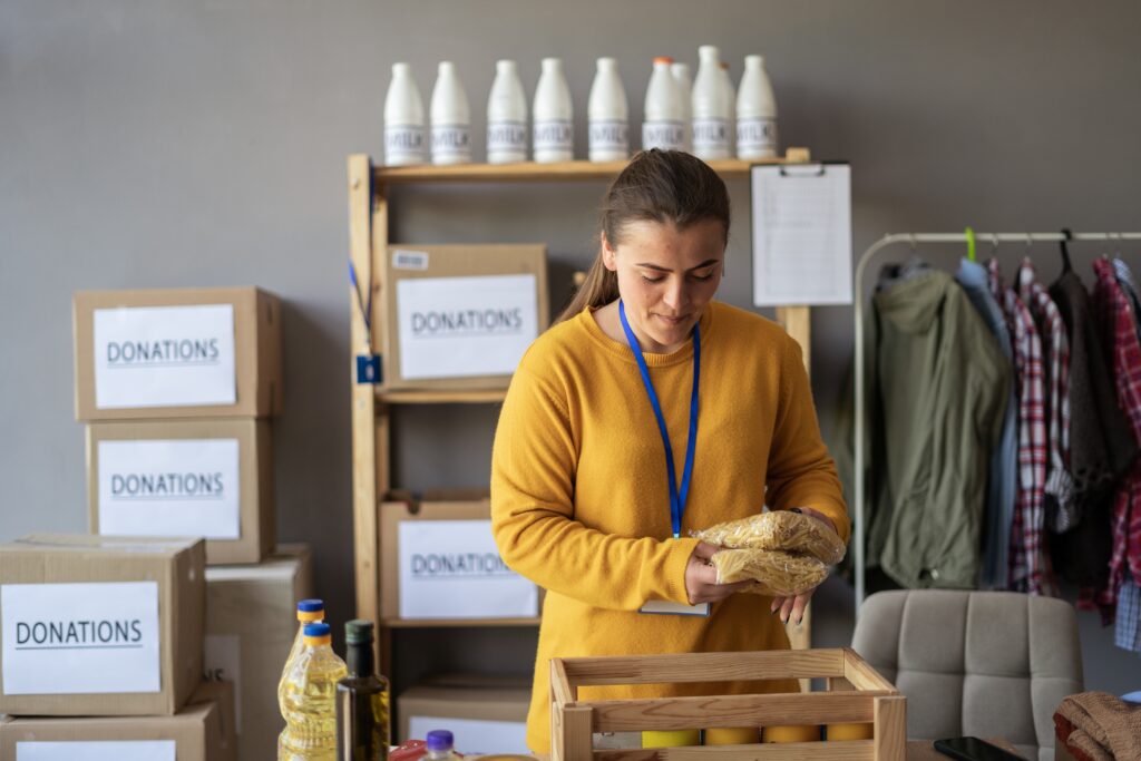 Volunteer in a donation center preparing inventory items, showcasing steps related to single audit (formerly a133 audit) compliance.