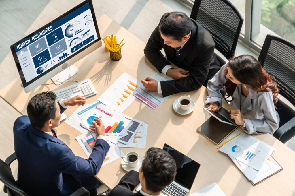 Business professionals in a human resources department discussing data relevant to a Form 5500 audit.