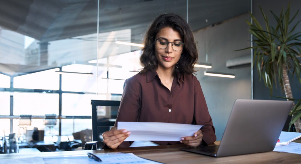 A female franchise owner reviews a document at her desk, highlighting the importance of the FDD Franchise Disclosure Document.