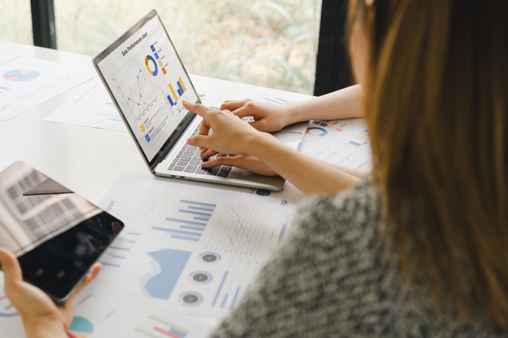 Two professionals reviewing financial charts on a laptop, discussing review engagements for companies.