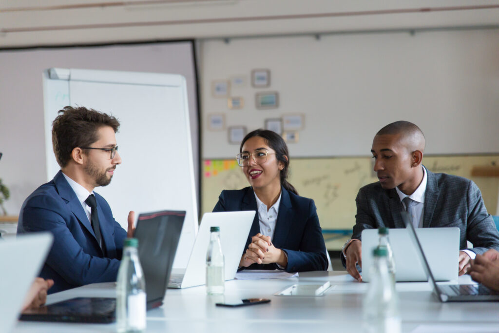 Group of cheerful managers communicating during meeting. Smiling young business people talking during briefing. Business meeting concept