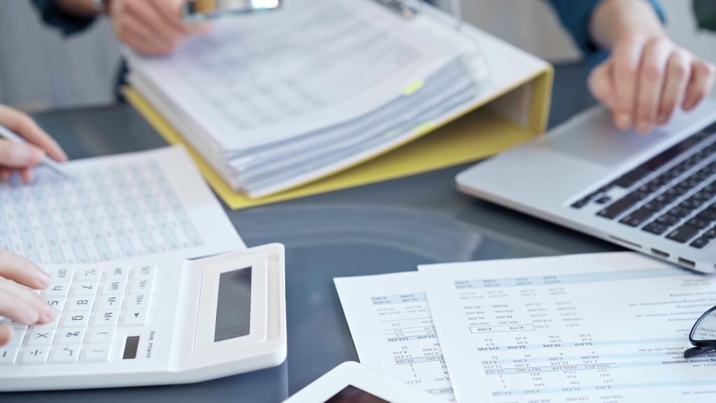 Close-up of accounting experts with a calculator and laptop during the month-end close process to finalize financial reports.