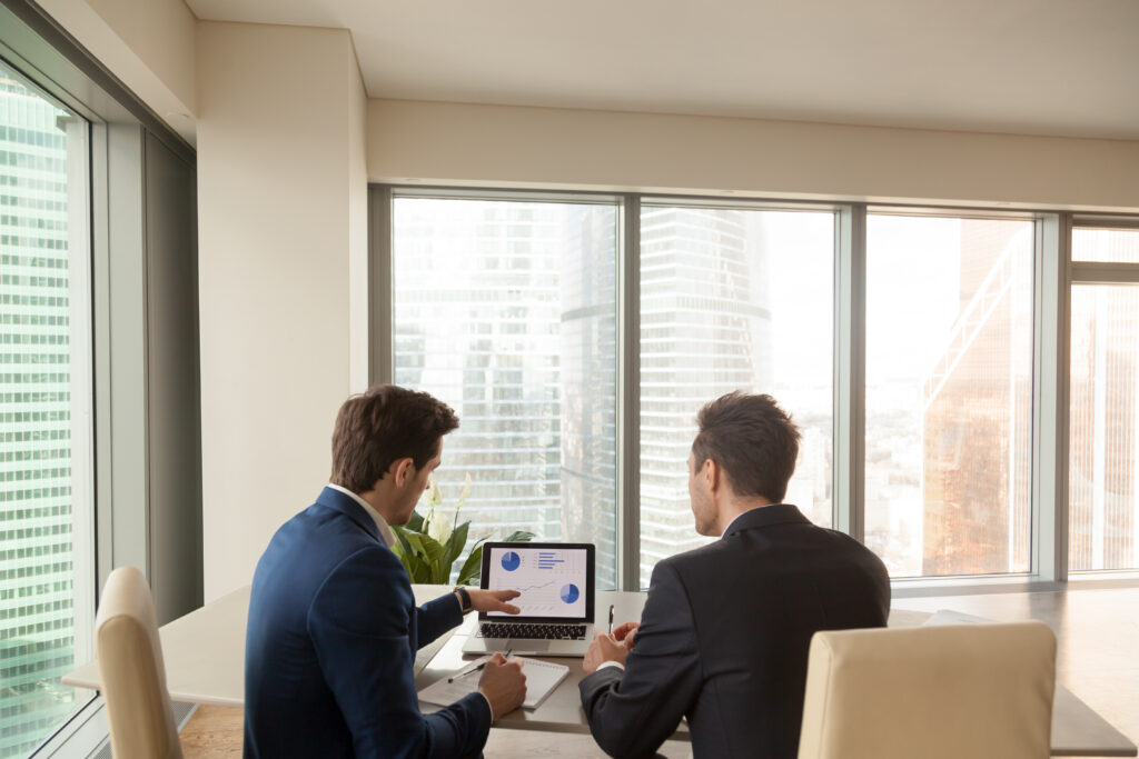 Two business professionals reviewing financial charts on a laptop, showcasing outsourced CFO services for strategic financial planning.