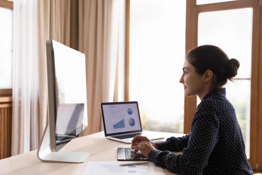 A female remote auditor carefully examines financial statements on her computer during a video call with a client.