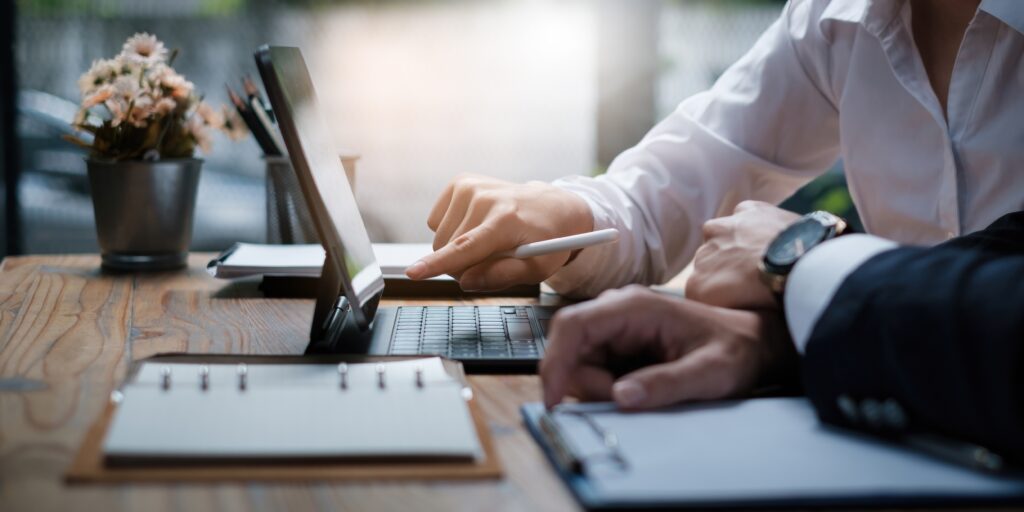 Business associates discussing data on a laptop, illustrating technical accounting advisory services for financial insights.