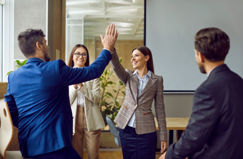 Team members high-five during a meeting, showing confidence and strong collaboration in audit preparedness efforts.