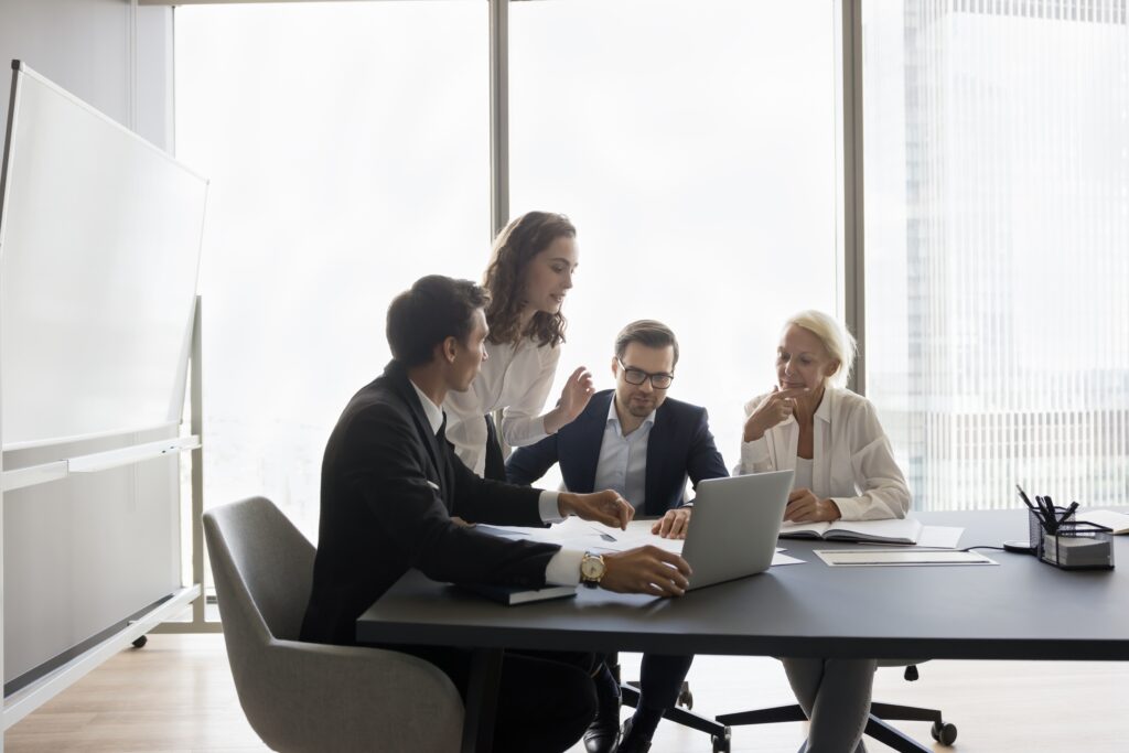 Professionals gather around a laptop, consulting with financial statement preparers to finalize financial disclosures.