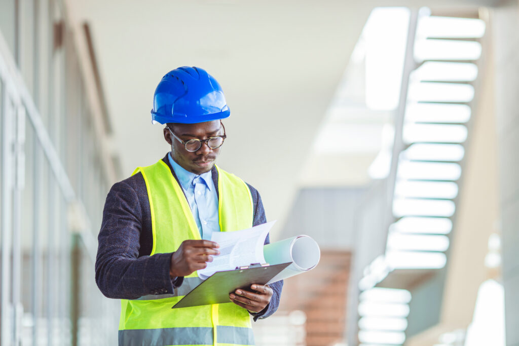 A project manager reviews plans and updates for WIP construction accounting at a job site.