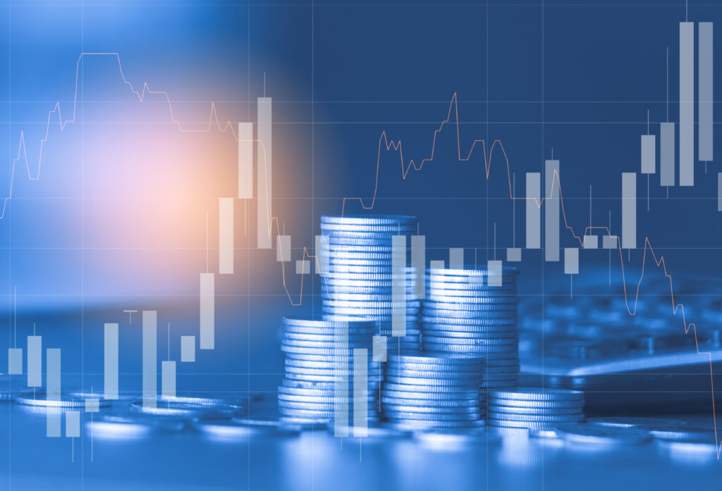 Stacks of coins and market charts representing how a REIT generates income through real estate investment.