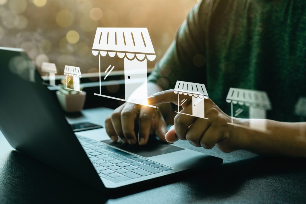 Hands type on a laptop with digital storefront icons floating above, representing franchise locations supported by a franchise cpa.