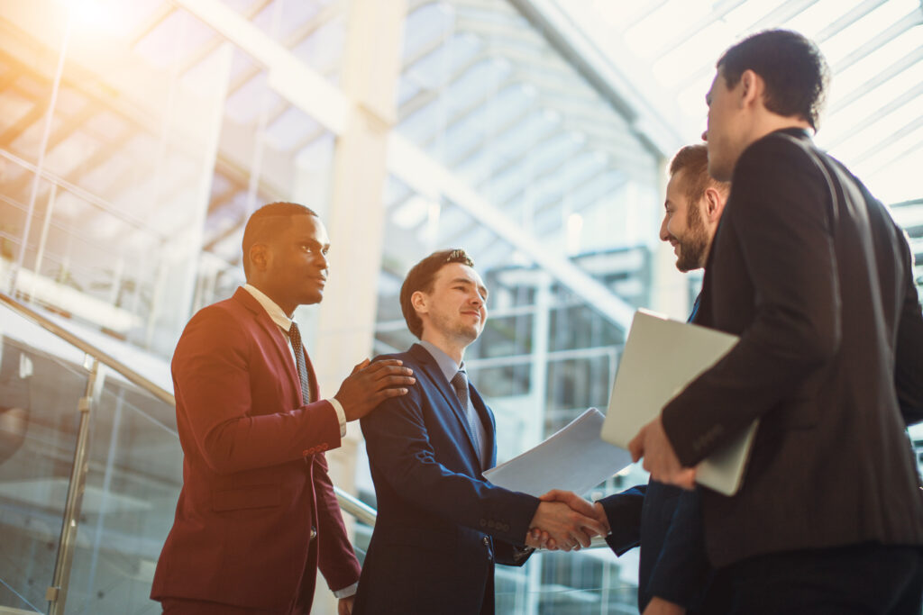 Small public accounting firms represented by professionals shaking hands and discussing documents in a bright office setting.