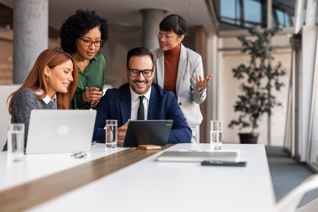 Team reviewing reports on a tablet and laptop while discussing auditing financial statements.