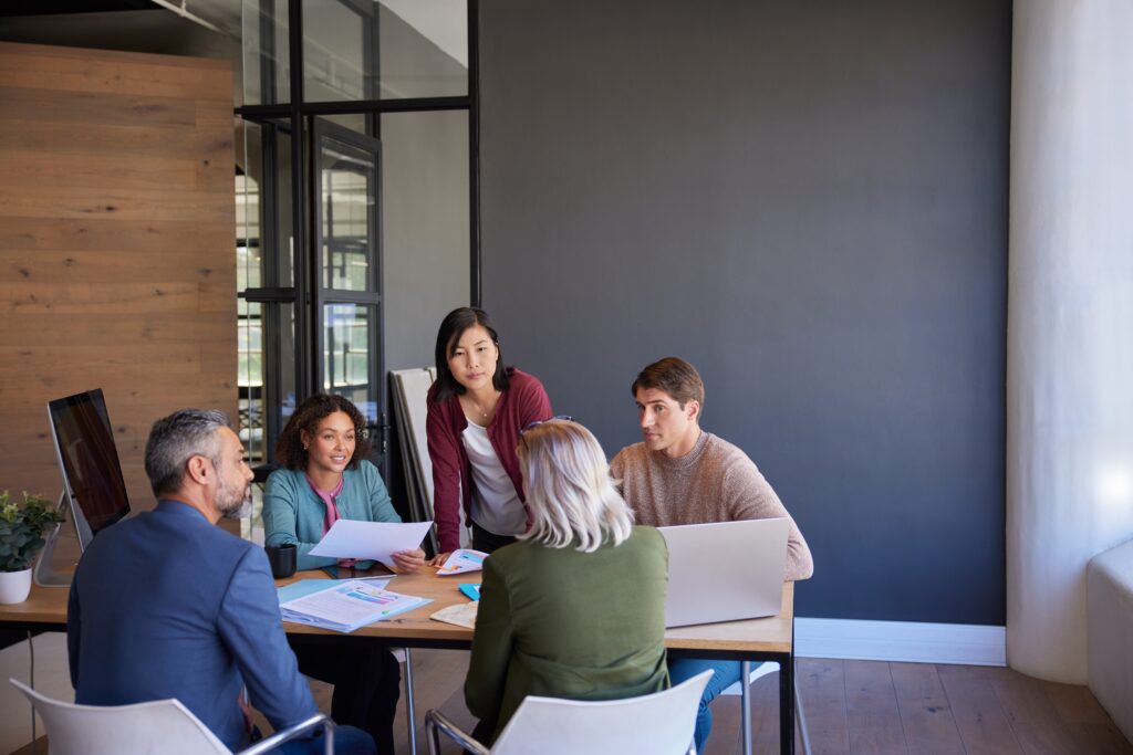 An IT risk assessment services discussion as team reviews reports around a conference table.