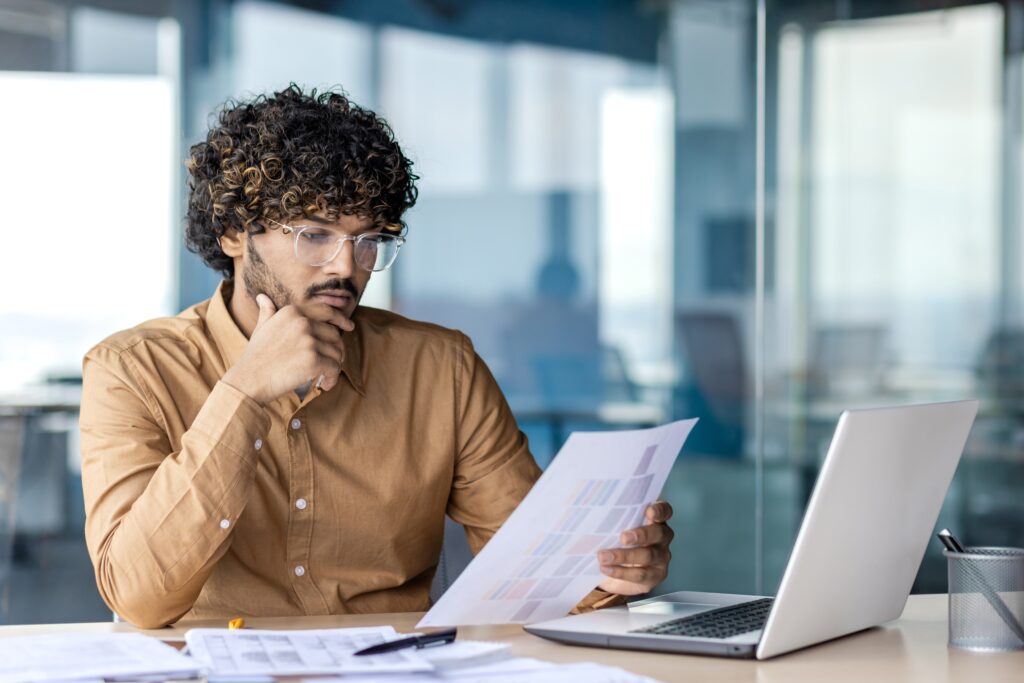 Limited assurance analysis with a professional reviewing documents beside a laptop.
