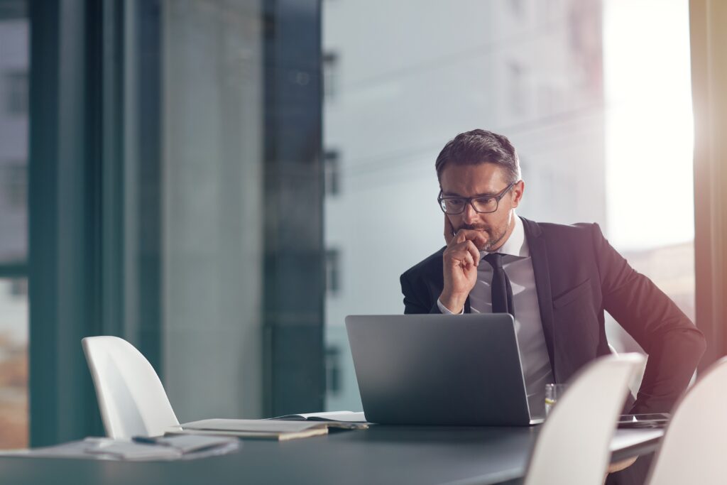 Audits vs agreed upon procedures reviewed by a business professional using a laptop at a conference table.