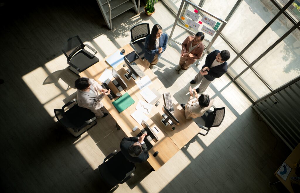 A startup team meets around office desks with charts and computers for IPO audit planning.