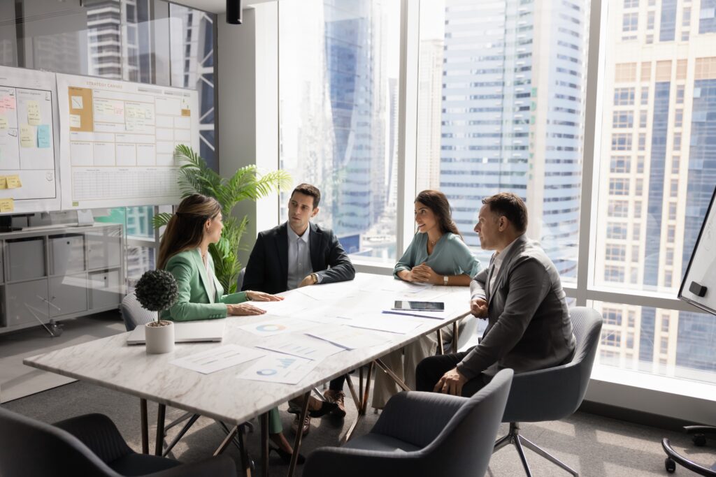 EBP auditor discussion in a bright conference room with reports, laptops, and planning boards.