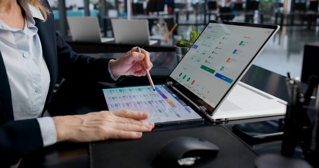 EBP auditor planning with a touchscreen laptop, charts, and business data in an office.