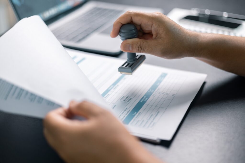 Professional stamps a financial document beside a laptop during a private company audit.