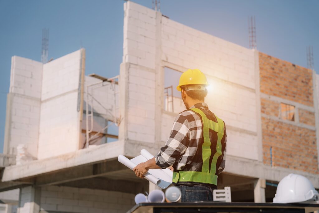 Work in progress construction accounting guides a professional reviewing blueprints at an active building site.