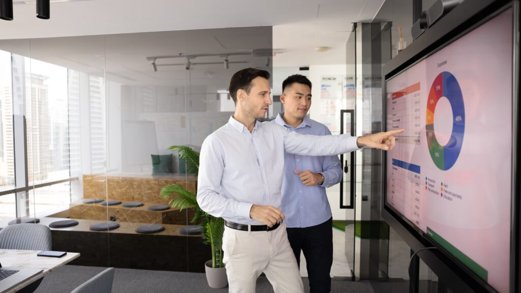 Team discusses HITRUST services while reviewing charts and graphs on a conference room screen.